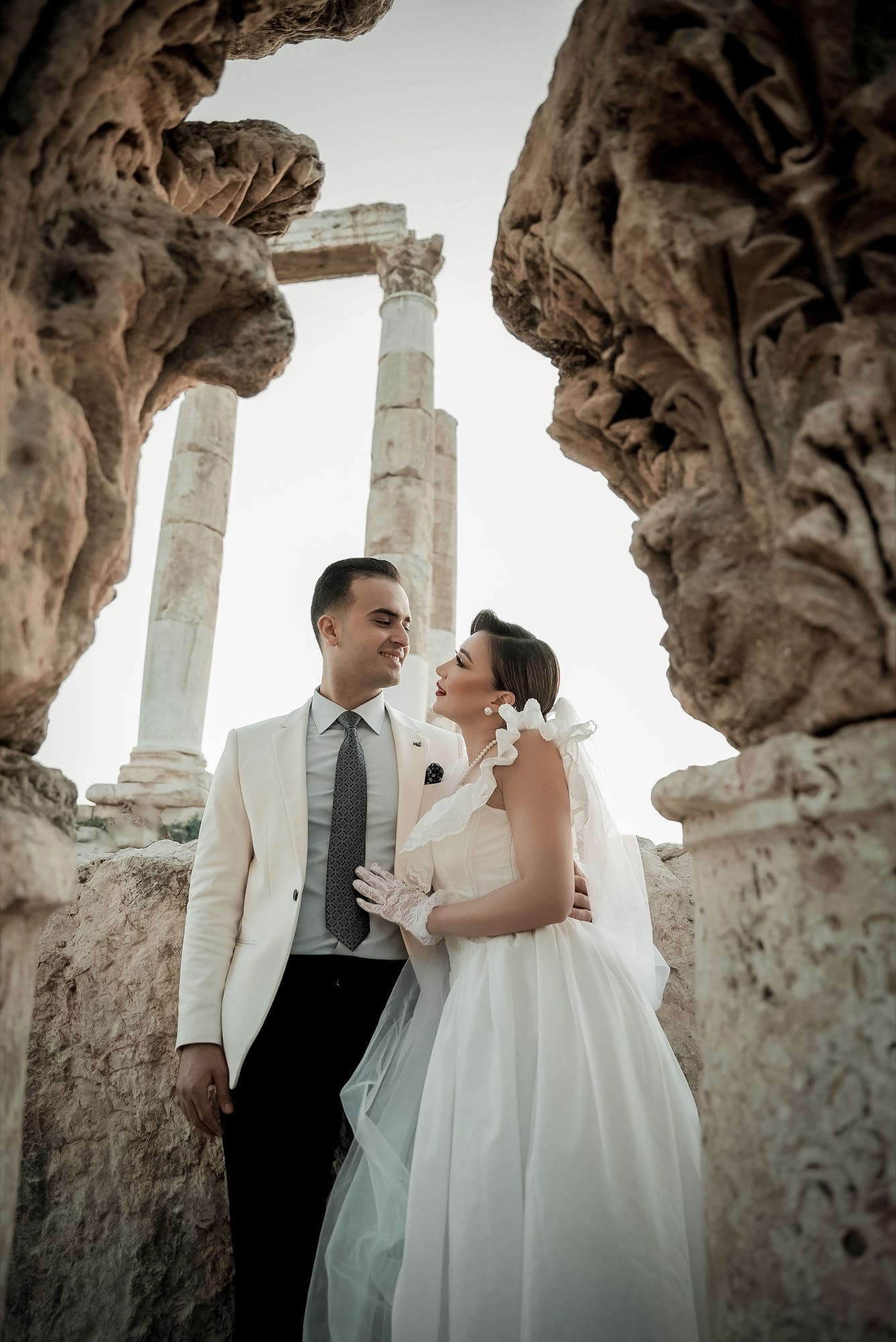 Bride and groom framed by ancient Roman columns at golden hour — editorial fine-art wedding portrait