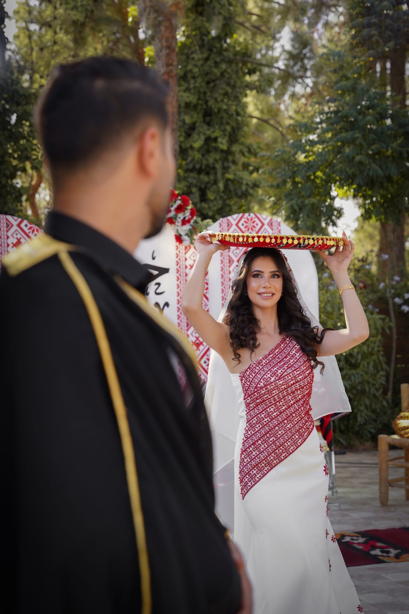 Bride in a traditional embroidered Arab gown carrying a decorated tray during a cultural pre-wedding ceremony, photographed by Veil & Light