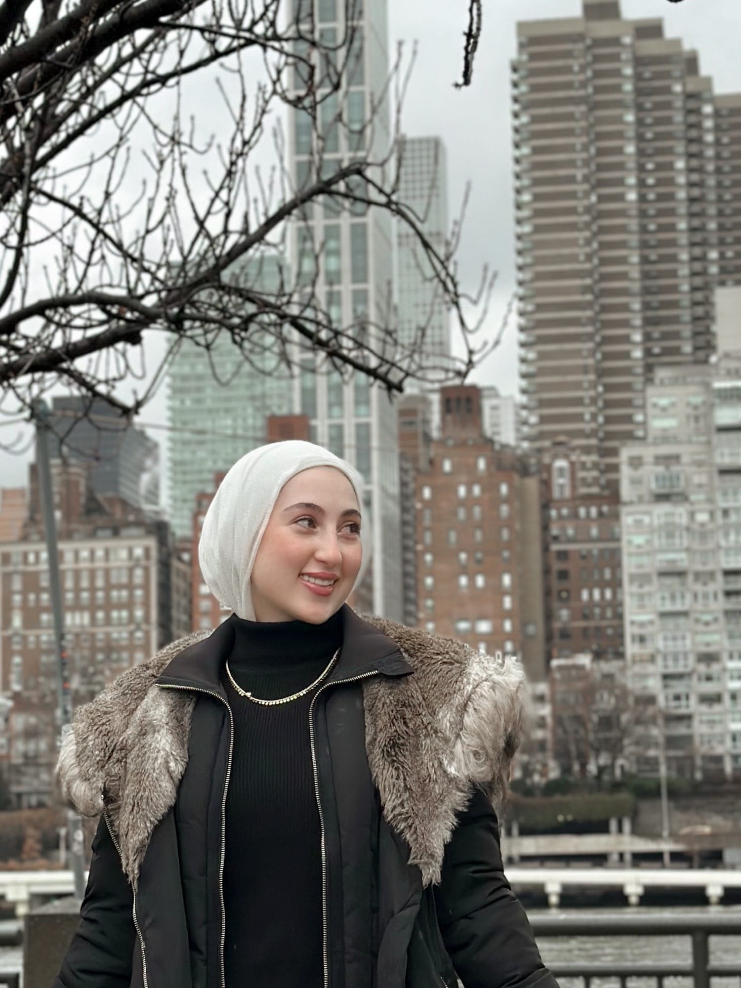 Farah Olabi, founder of Veil & Light, photographed along the East River with the Manhattan skyline behind her
