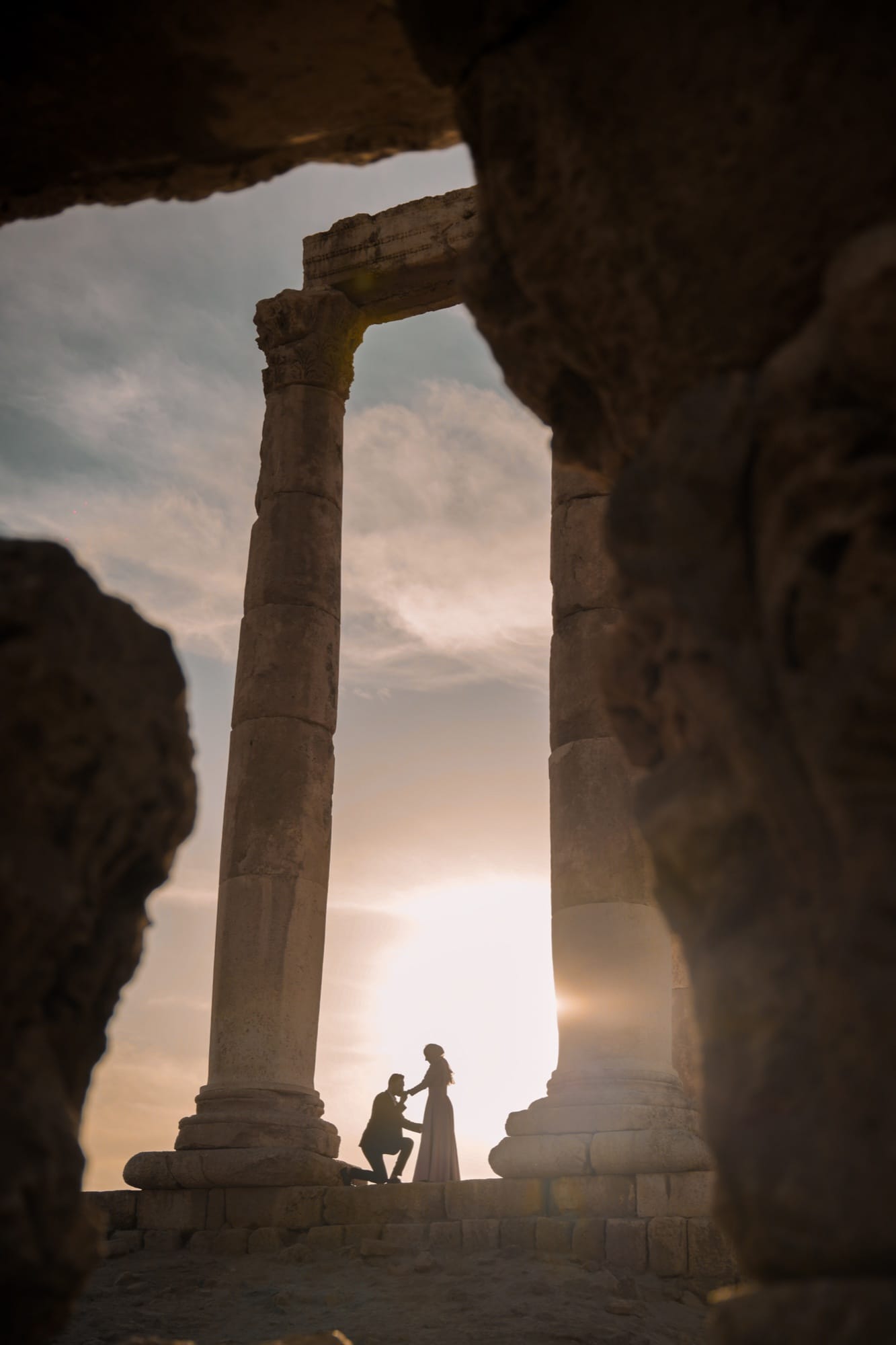 Cinematic silhouette of a couple framed by ancient stone columns at golden hour — fine-art wedding photography by Veil & Light